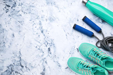 Sports water bottle, shoes and jumping rope on white background