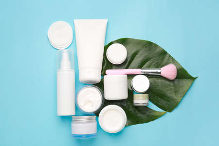 Different cosmetic creams with brush on color background