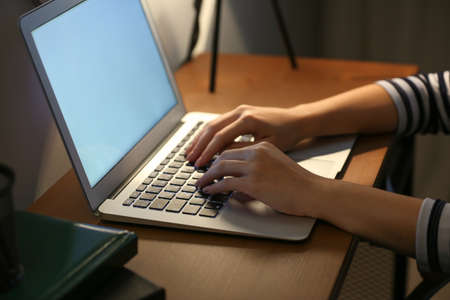 Young woman working on laptop at table in eveningの写真素材