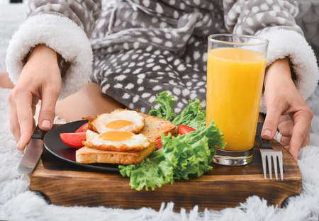 Young woman having tasty breakfast in bed, closeup