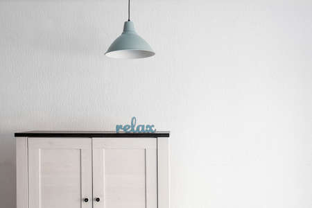 Stylish commode with lamp near white wallの写真素材
