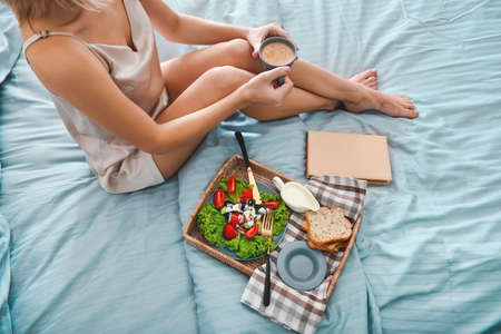 Young woman having tasty breakfast in bedの写真素材