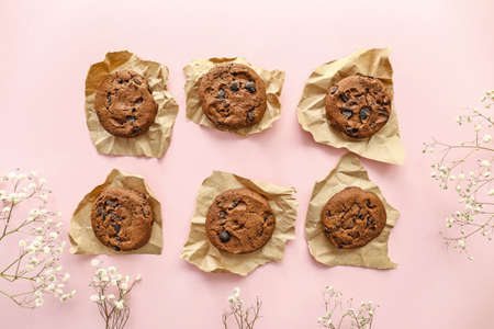 Tasty chocolate cookies and flowers on color backgroundの写真素材