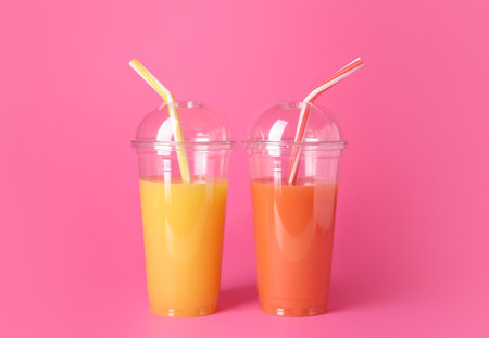 Plastic cups of fresh juices on color backgroundの写真素材