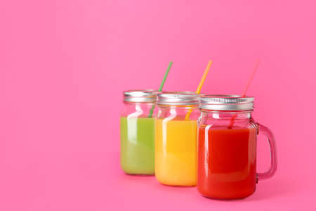 Mason jars of fresh juices on color backgroundの写真素材