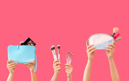 Many hands with decorative cosmetics and makeup brushes on color backgroundの写真素材