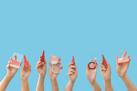 Many hands with decorative cosmetics on color background