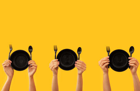 Many hands with plastic tableware on color backgroundの写真素材
