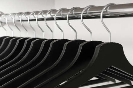Rack with clothes hangers on white background, closeup