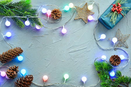 Christmas composition with glowing garland and gift on gray background