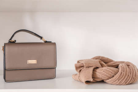 Stylish female bag and scarf on shelf in wardrobeの写真素材