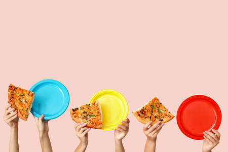 Many hands with pieces of pizza and plates on color backgroundの写真素材