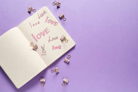 Open notebook with written words LOVE on color background