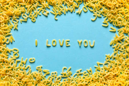 Phrase I LOVE YOU made of dry pasta on color background