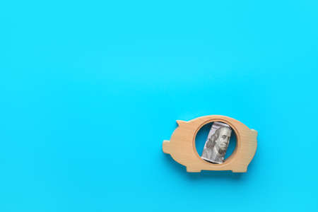 Piggy bank with dollar banknote on color backgroundの写真素材