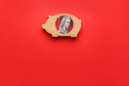 Piggy bank with dollar banknote on color backgroundの写真素材