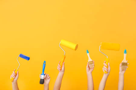 Female hands with painter's tools on color backgroundの写真素材