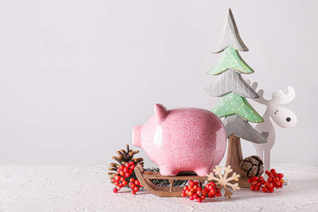 Piggy bank with Christmas decor on light backgroundの写真素材