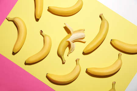 Peeled banana among unpeeled ones on color background. Concept of uniquenessの写真素材