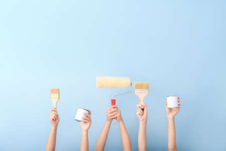 Female hands with painter's tools on color backgroundの写真素材