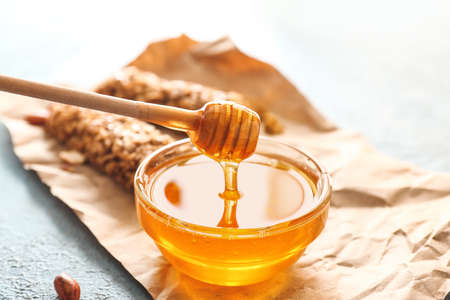 Bowl with tasty honey and spoon on color backgroundの写真素材