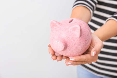Woman with piggy bank on light background, closeupの写真素材