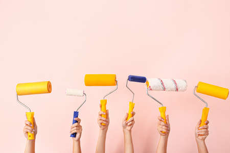 Female hands with paint rollers on color backgroundの写真素材