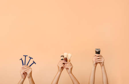 Hands with different tools for shaving on color background