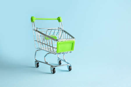 Empty small shopping cart on color backgroundの写真素材