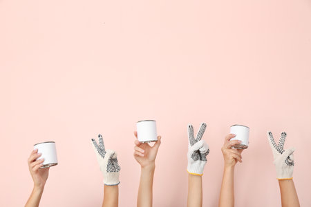 Female hands with cans of paint on color backgroundの写真素材