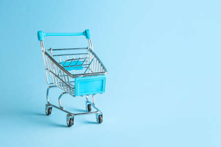 Empty small shopping cart on color backgroundの写真素材