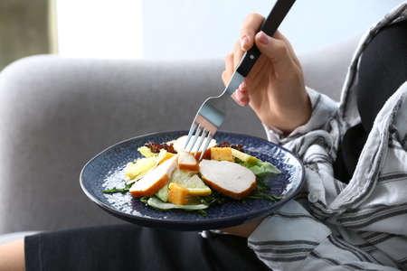 Woman eating tasty salad at home