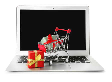 Laptop and small cart with gift boxes on white background. Internet shopping conceptの写真素材