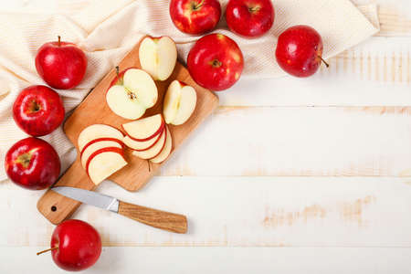 Fresh ripe apples with cutting board and knife on white wooden backgroundの写真素材