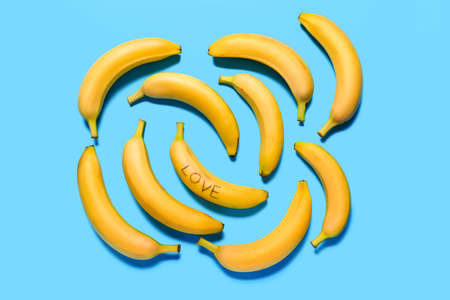 Many fresh bananas with word LOVE on color backgroundの写真素材