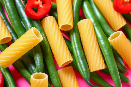 Dry pasta with fresh vegetables on color background, closeupの写真素材