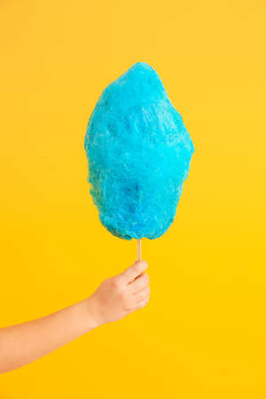 Female hand with tasty cotton candy on color backgroundの写真素材