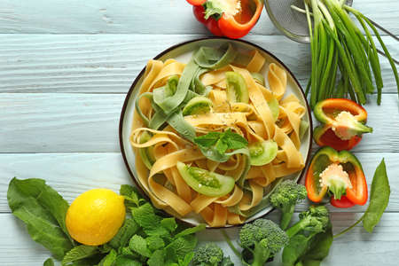 Plate with tasty pasta and fresh vegetables on table