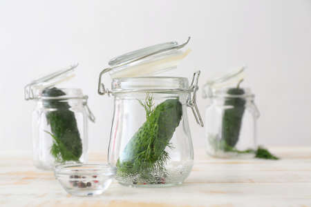 Jars with fresh cucumbers on white tableの写真素材