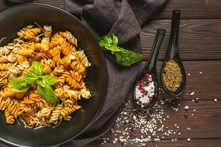 Plate with tasty pasta and spices on wooden tableの写真素材