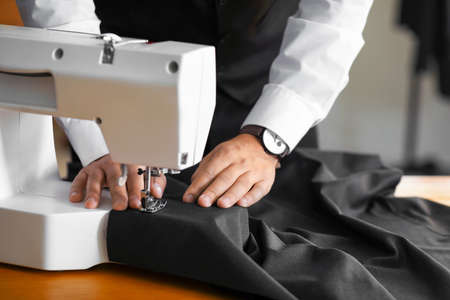 Young male tailor working on sewing machine in atelierの写真素材