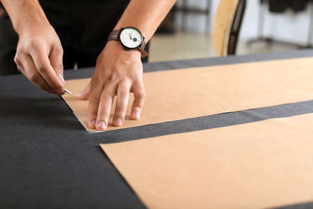 Young tailor working at table in atelier, closeupの写真素材