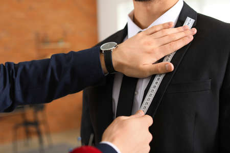 Male tailor taking client's measurements in atelier