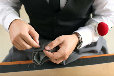Young tailor working at table in atelier, closeupの写真素材