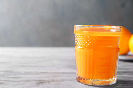 Glass of fresh orange juice on gray tableの写真素材