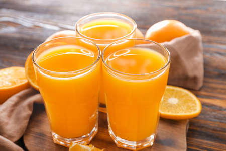 Glasses of fresh orange juice on wooden tableの写真素材