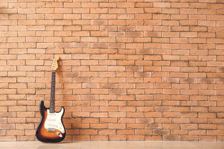 Modern bass guitar near brick wallの写真素材