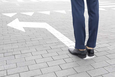 Young businessman standing on road with arrow marking. Concept of choiceの写真素材