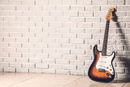 Modern bass guitar near brick wallの写真素材