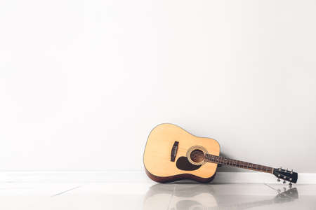 Modern acoustic guitar near white wallの写真素材